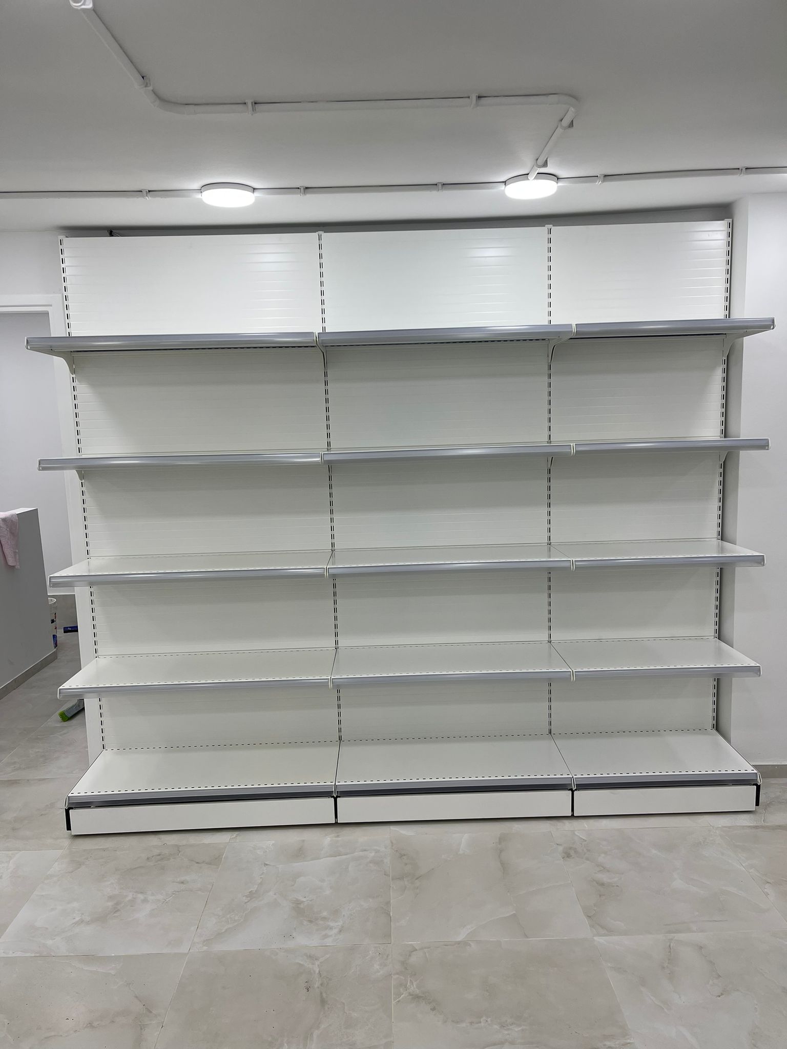 מדפים מרכזיים דו־צדדיים בסופר שכונתי — התקנה של לוגיסטי מדף